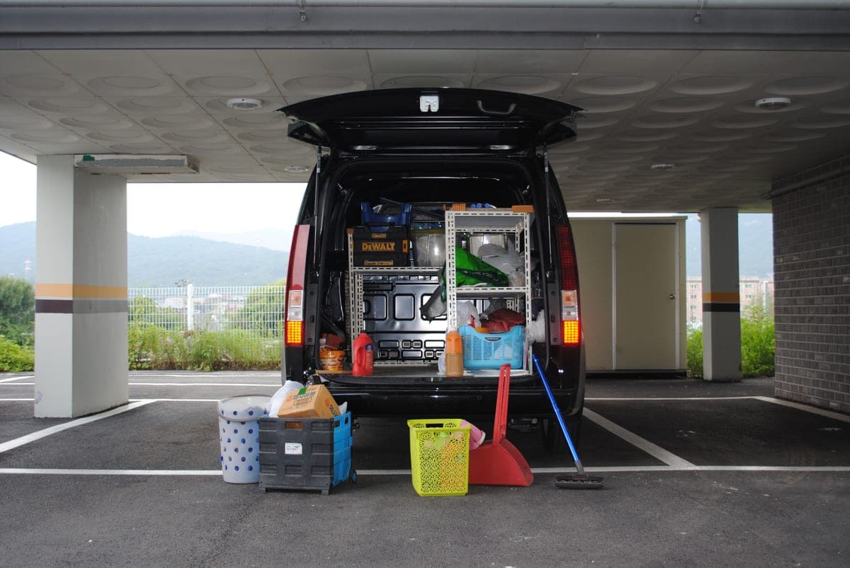 Tradesperson loading supplies into a work van outside a job site